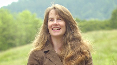 Professor Mary Wood smiles and holds a Natural Resources Law textbook she coauthored.