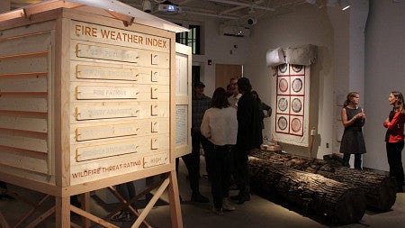 Gallery visitors stand around artworks created by the Fuel Ladder collective for their project, "Ignition"