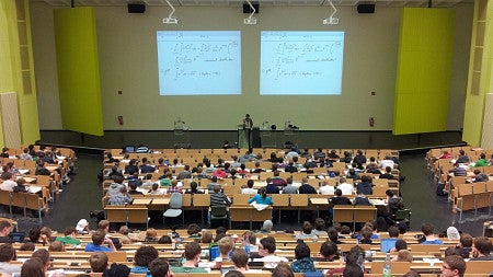 A lecture hall packed with people listening to a presentation at the State of Immigrants Conference