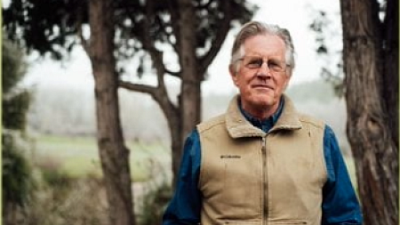 William deBuys looks into the camera as he poses for a picture in front of a few trees