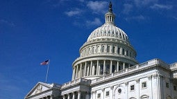 The capitol building is shown against a blue sky with a few wispy clouds. 