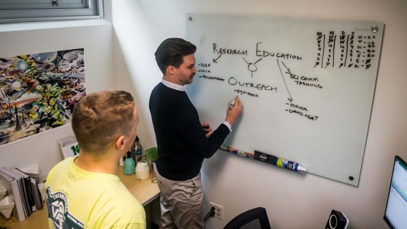 Center for Science Communication Research program assistant Ian Winbrock (right) explains the center's priorities to a student.