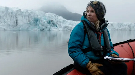 M Jackson sits in a watercraft and looks across a glacial landscape