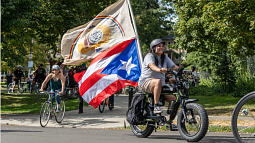 Alexis Vasquez, who uses they/them pronouns and identifies as Taino, proudly displays the Navajo Nation and Puerto Rico flags as they lead the cyclists to the next stop during the ride. 