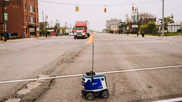 A Kiwibot delivery robot trying to cross Michigan Avenue in Detroit.