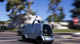 A delivery robot drives down a residential street. 