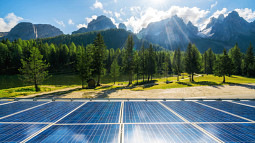 Mountains and trees serve as the backdrop to a set of solar panels