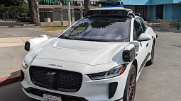 An autonomous Jaguar is parked by a curb. 