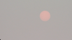 The sun looks dim and orange behind a screen of thick wildfire smoke